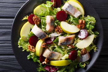 Fresh mackerel salad with apples, walnuts, beets and mix lettuce close-up on a plate. horizontal...