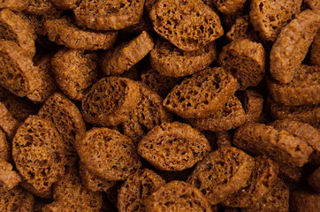 Roasted pieces dry brown bread as background, top view, closeup..