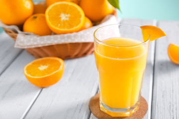 Glass with fresh orange juice and fruit on wooden table
