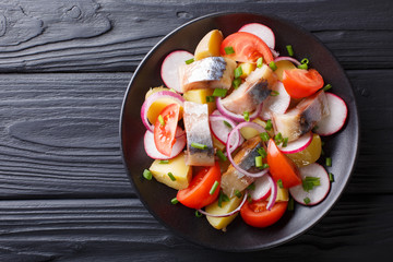 Delicious salad of smoked mackerel with potatoes, radish and tomatoes close-up. horizontal top view