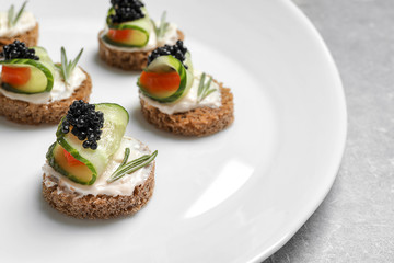 Tasty appetizer with black caviar and cucumber on plate