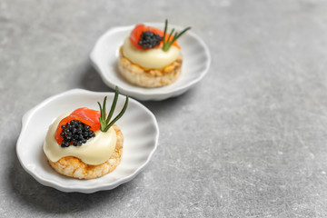 Tasty appetizer with black caviar and salmon on plates