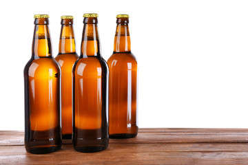 Glass bottles of beer on table against white background