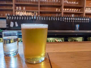 Glass of beer on bar counter top, next to water glass