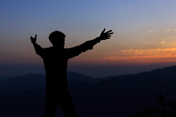 Man with arms extended toward heaven at sunrise ,success or prayer concept