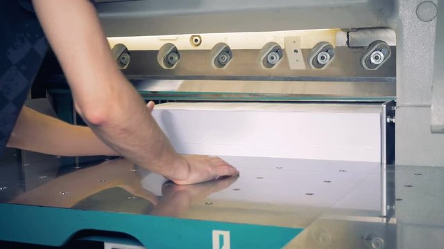 Male worker cutting a stack of paper in a typography.