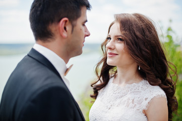 Wedding couple at breathtaking landscape with rock and lake.