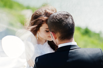 Wedding couple at breathtaking landscape with rock and lake.