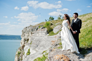 Wedding couple at breathtaking landscape with rock and lake.