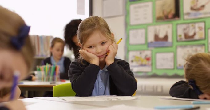 4k, Cute little school girl day dreaming beside her classmate in classroom. Slow motion