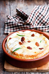 Delicious  hot baked camembert with sultanas on wooden table
