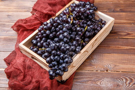 Image of black grapes in wooden box with claret cloth