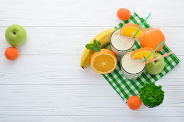 Smoothies with bananas and oranges, a sprig of mint on a white background. Space for text or design.