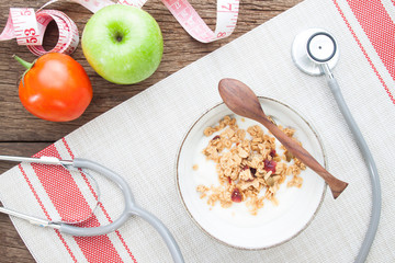 Yogurt with granola in a bowl and stethoscope on wooden table, Healthy lifestyle concept