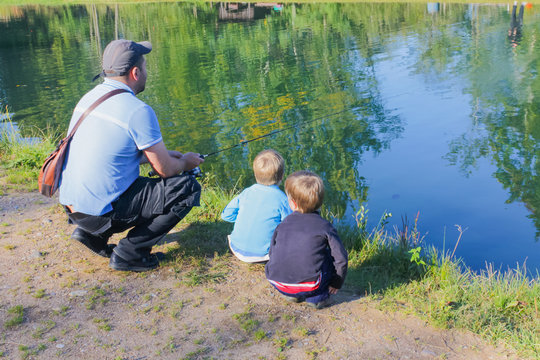 Dad and children are fishing. Dad and two sons are fishing.