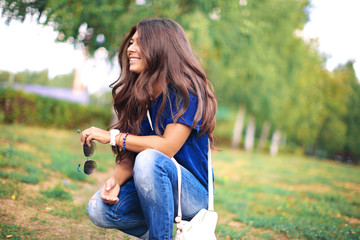 beautiful young happy woman resting in green park, squatting and smiling