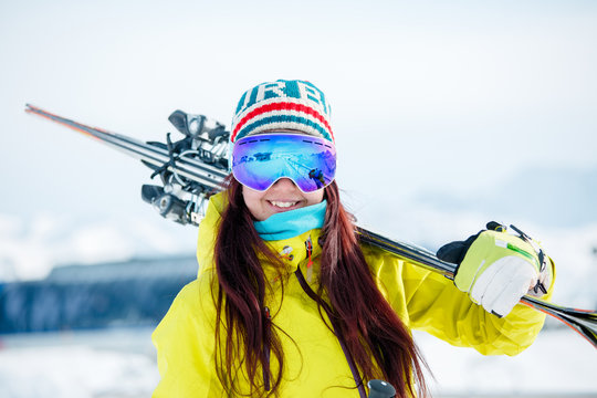 Photo of smiling sporty woman in mask with skis on her shoulder