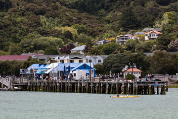 A view of Akaroa, New Zealand from the sea with cruise boat passengers enjoying the town