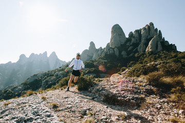 Fast and strong, fit athletic man runs on mountain path or trail during ultra marathon race, hard...