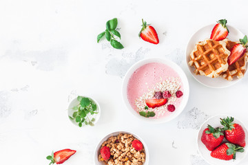Breakfast with muesli, strawberry smoothie, waffles, fruits on white background. Flat lay, top view, copy space