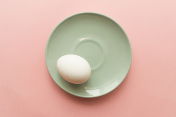 One white egg on pink pastel background. minimal concept. top view