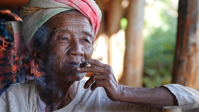 Old lady of Pa'O ethnic minority smoking a Burmese cigar at Indein village near Inle Lake, Shan State, Myanmar (Burma).
