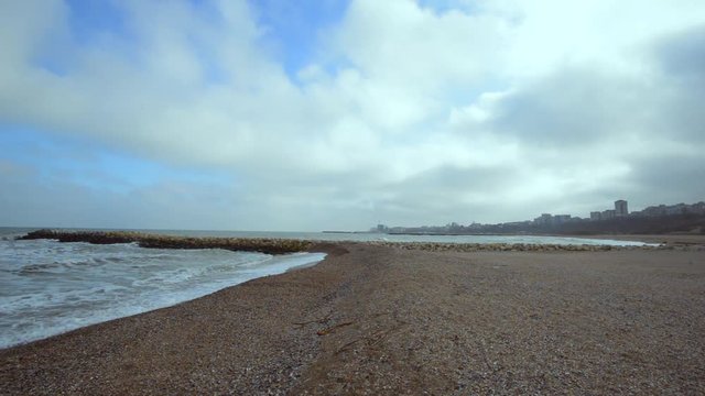 Waves and wind in a cold winter day at the black sea beach with Tomis port  in the background