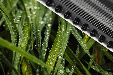 Grass on a background of iron details. Background image of the interaction of nature and technology.