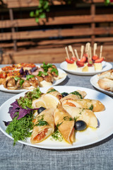 Delicious thin pancakes with salmon, dill and olives on white plate on dinner table outdoors, free space. Russian cuisine. Maslenitsa. Rolls of thin pancakes with smoked salmon