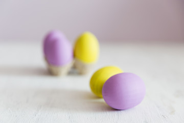 Easter postcard. Violet and yellow Easter eggs on a white vintage background. Copy space.