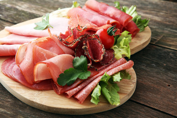 Food tray with delicious salami, pieces of sliced ham, sausage, tomatoes, salad and vegetable - Meat platter with selection