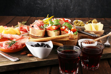 Italian antipasti wine snacks set. Cheese variety, Mediterranean olives, pickles, Prosciutto di Parma, tomatoes, artichokes and wine in glasses