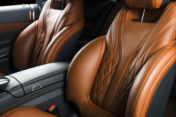 Modern Luxury car inside. Interior of prestige modern car. Comfortable leather seats. Brown perforated leather cockpit with isolated Black background. Modern car interior details