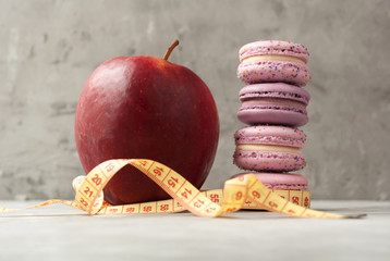 Close-up view of apple, macarons and measuring tape. Concept of nutrition