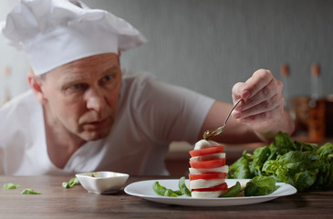 Chef prepares a snack with mozzarella and pesto sauce .