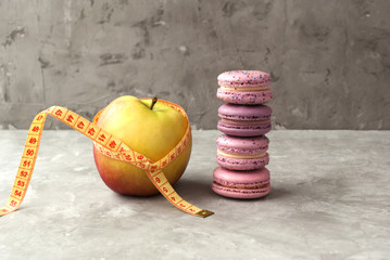 Close-up view of apple, macarons and measuring tape. Concept of nutrition