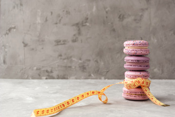 Pink macarons and measuring tape. Concept of diet.