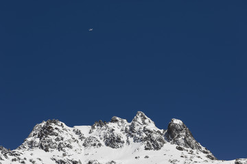Snow-covered, fresh white mountain peak with a plane in the Alps of Switzerland
