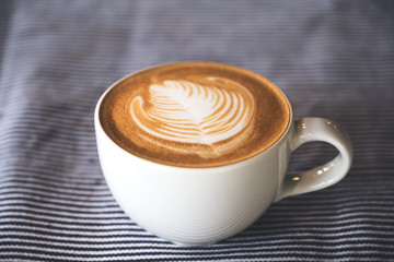 Closeup image of a cup of hot latte coffee with latte art