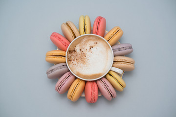 Pastel macarons around a coffee cup