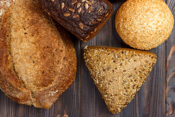 Assortment of baked bread on dark wooden background. Bakery and grocery food store concept. Flat lay with space for text