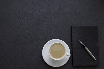 Flat lay Man set: cup of coffee, tie, pen and notepad. Top view Black background