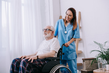 Obraz premium Nurse pushing wheelchair with senior man
