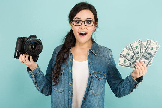 Young surprised woman with camera and cash