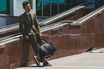 A man in a classic khaki suit, standing in the expectation of a business center in the hands of a...