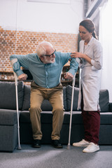 Doctor helping senior patient with crutches