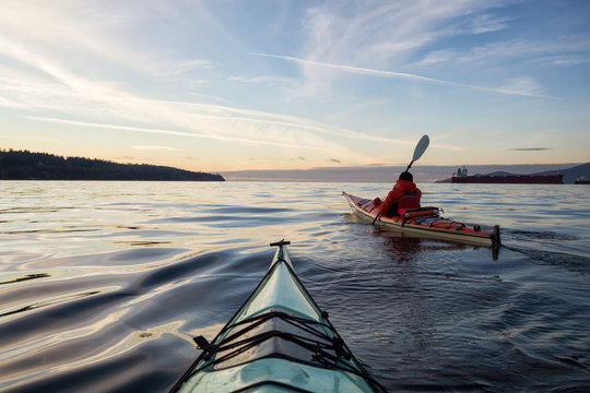 Man on Sea Kayak is kayaking during a vibrant winter sunset. Taken near Jericho Beach, Vancouver, BC, Canada.