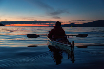 Naklejka na ściany i meble Man on Sea Kayak is kayaking during a vibrant winter sunset. Taken near Jericho Beach, Vancouver, BC, Canada.