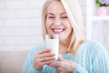 Happy middle aged woman drinking milk