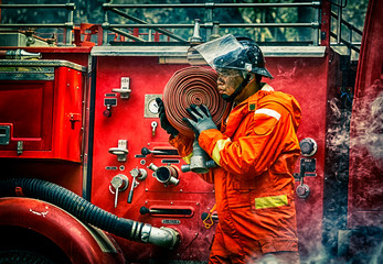 Fototapeta premium Emergency Fire Rescue training, firefighters in uniform, carry a water hose run through flame